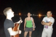 Hostel guest from Brazil entertains other guests on Easton's Beach by the light of a full moon.