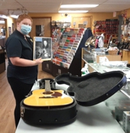 Staff person at Rick's Musical Instruments accepting the donation of Sid's guitar as part of their partnership with the Newport Festivals Foundation